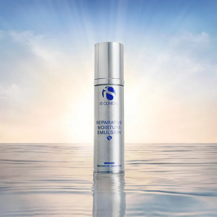Silver bottle of iS Clinical Reparative Moisture Emulsion 50g standing on reflective water surface with sunrise background