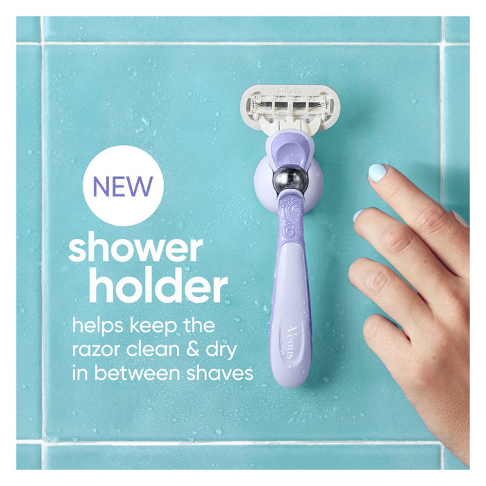 Gillette Venus Extra Smooth Swirl Razor in purple on teal tile with suction shower holder; text reads "NEW shower holder"