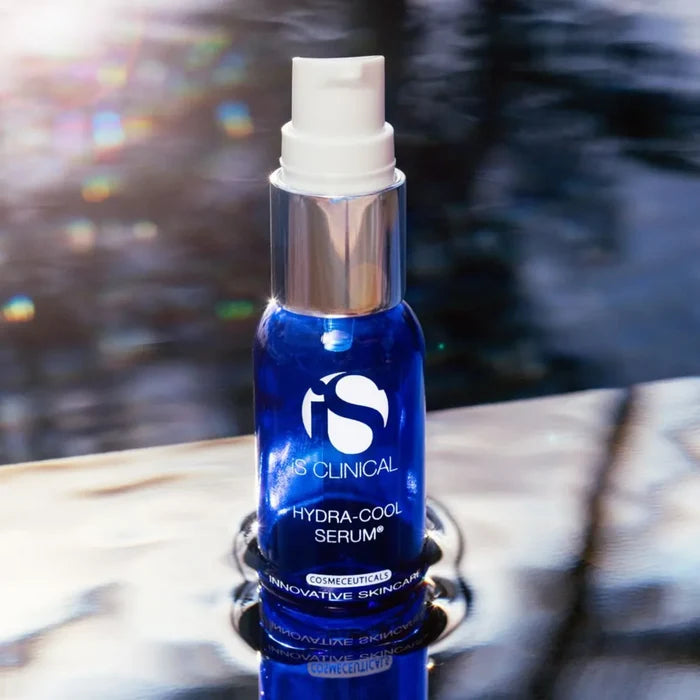 Blue glass bottle of iS Clinical Hydra-Cool Serum with white pump and silver collar on reflective surface