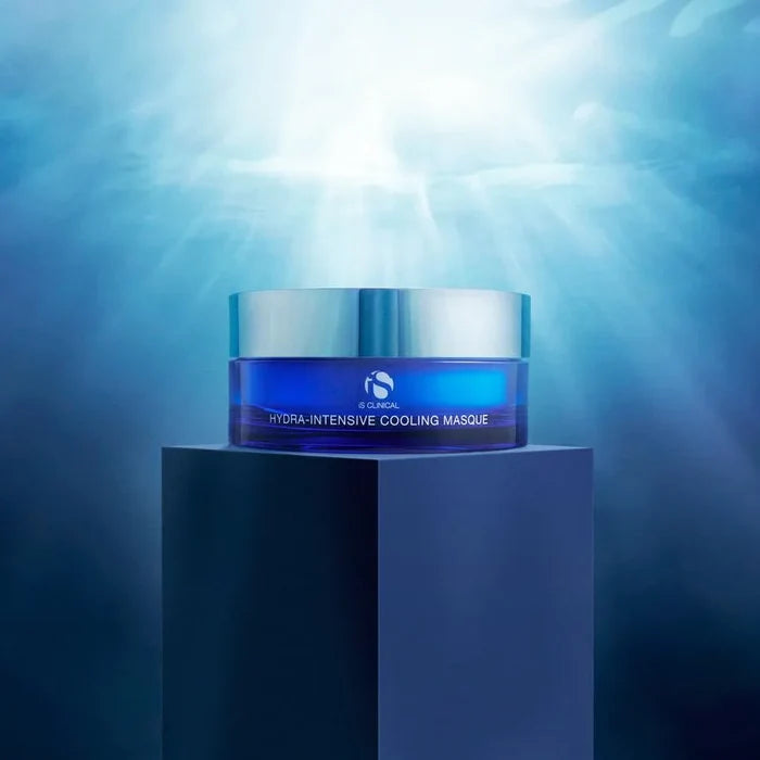 Blue jar of iS Clinical Hydra-Intensive Cooling Mask with silver lid on dark pedestal under light rays