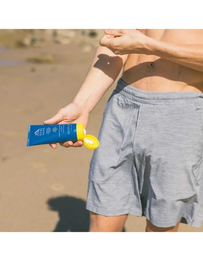 Applying Oars + Alps sunscreen lotion on beach