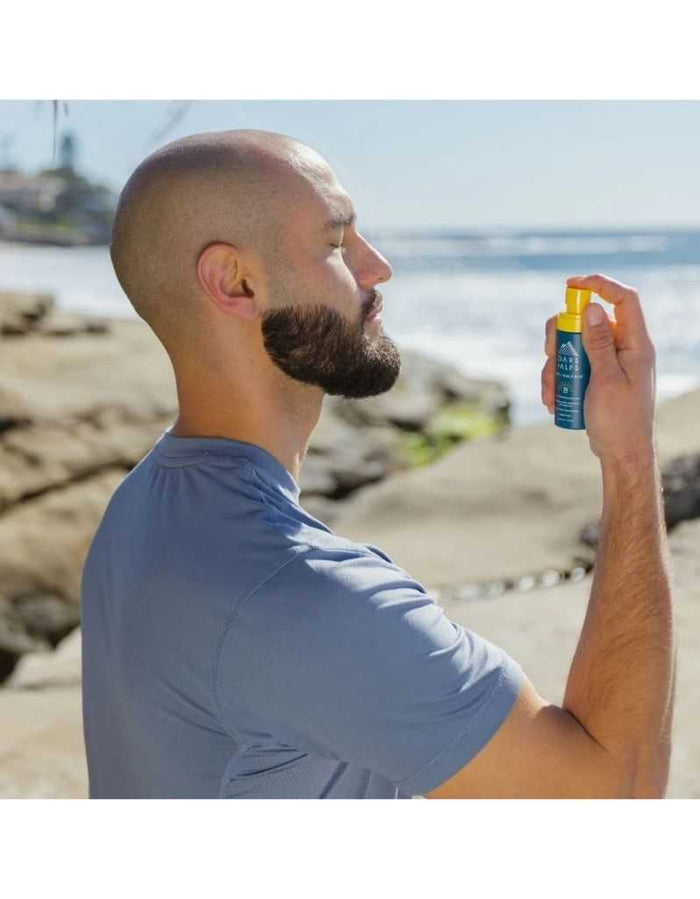 Man using Oars + Alps SPF 35 mist on head at beach