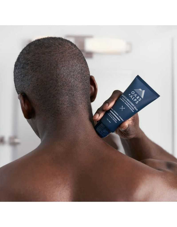 Applying Oars + Alps Muscle Recovery Balm on neck for muscle relief