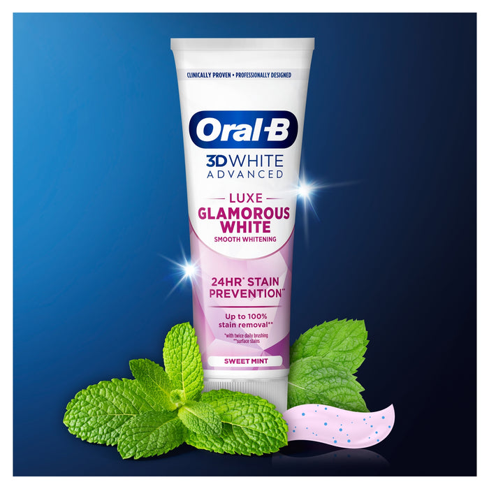 Oral-B 3D White Advanced Luxe Glamorous White toothpaste tube on blue background, surrounded by mint leaves with pink toothpaste swirl.