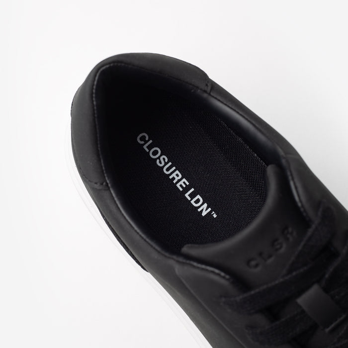 Sole view of the Premium Classic Trainer in black, showing the textured Closure LDN custom outsole and embossed branding.