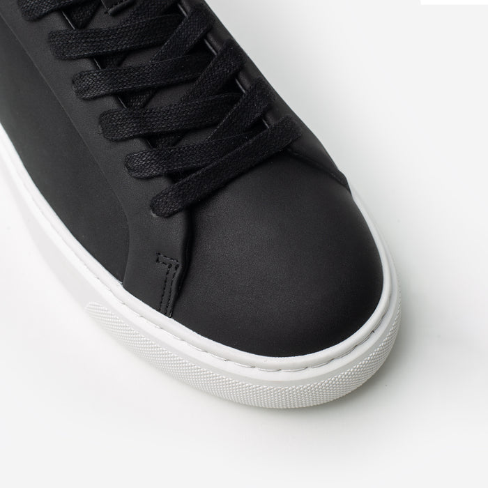 Close-up of the Premium Classic Trainer in black, highlighting the smooth black PU toe box, tonal lace-up fastening, stitching and textured cup sole.