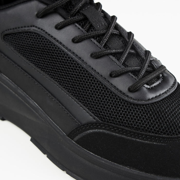 Close up shot of premium runner trainer in all black, showing black mesh panel and black laces