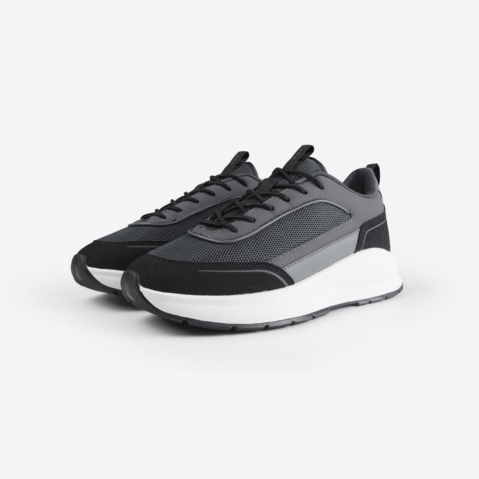 Pair of black runner trainers with grey panels shot on white background
