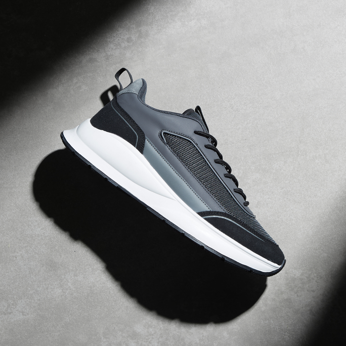 Side shot of black premium runner under a spotlight