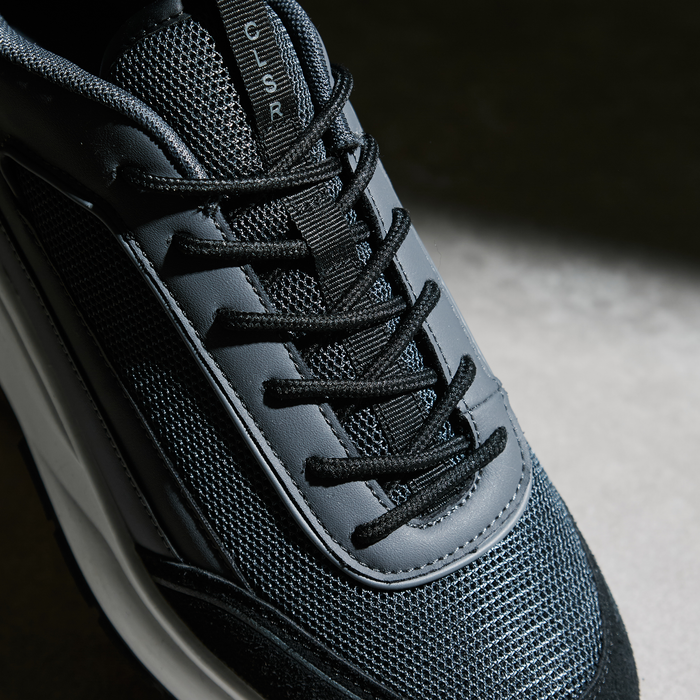 Zoomed in shot of black runner trainer focusing on laces and mesh panelling