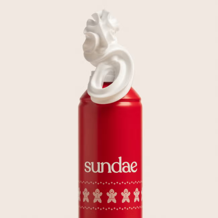 Sundae Gingerbread Shower Foam red can with whipped foam nozzle and gingerbread man pattern on cream background.