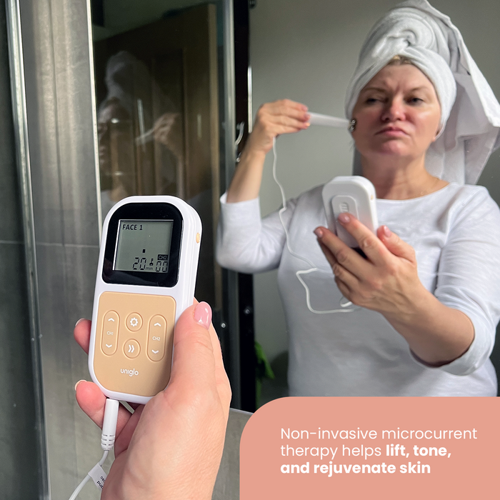 TensCare Uniglo device held in foreground showing "FACE 1" on display; woman with towel wrap uses Uniwand wand on face in mirror background.