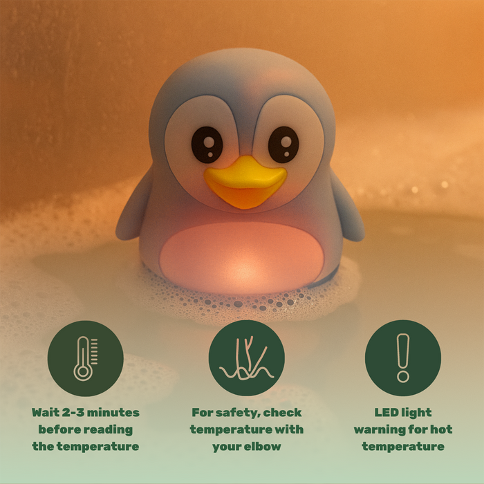 TensCare Zoo Friends Bath Thermometer penguin toy floating in bubbly water, warm orange background, LED light glowing pink