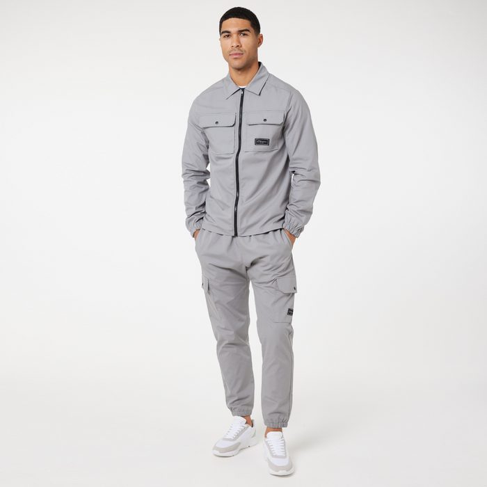 Model wearing full matching set including ice grey men's overshirt zipped up and the utility cargo pants
