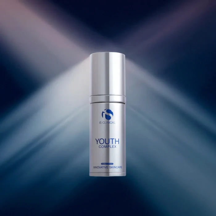 Silver pump bottle of iS Clinical Youth Complex with blue logo and text on dark blue background