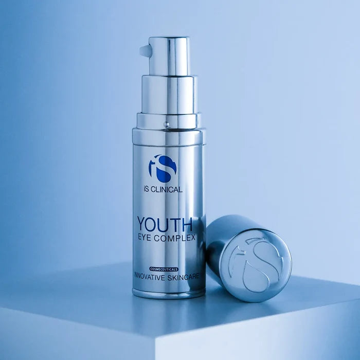 Silver pump bottle of iS Clinical Youth Eye Complex with detached cap on white surface